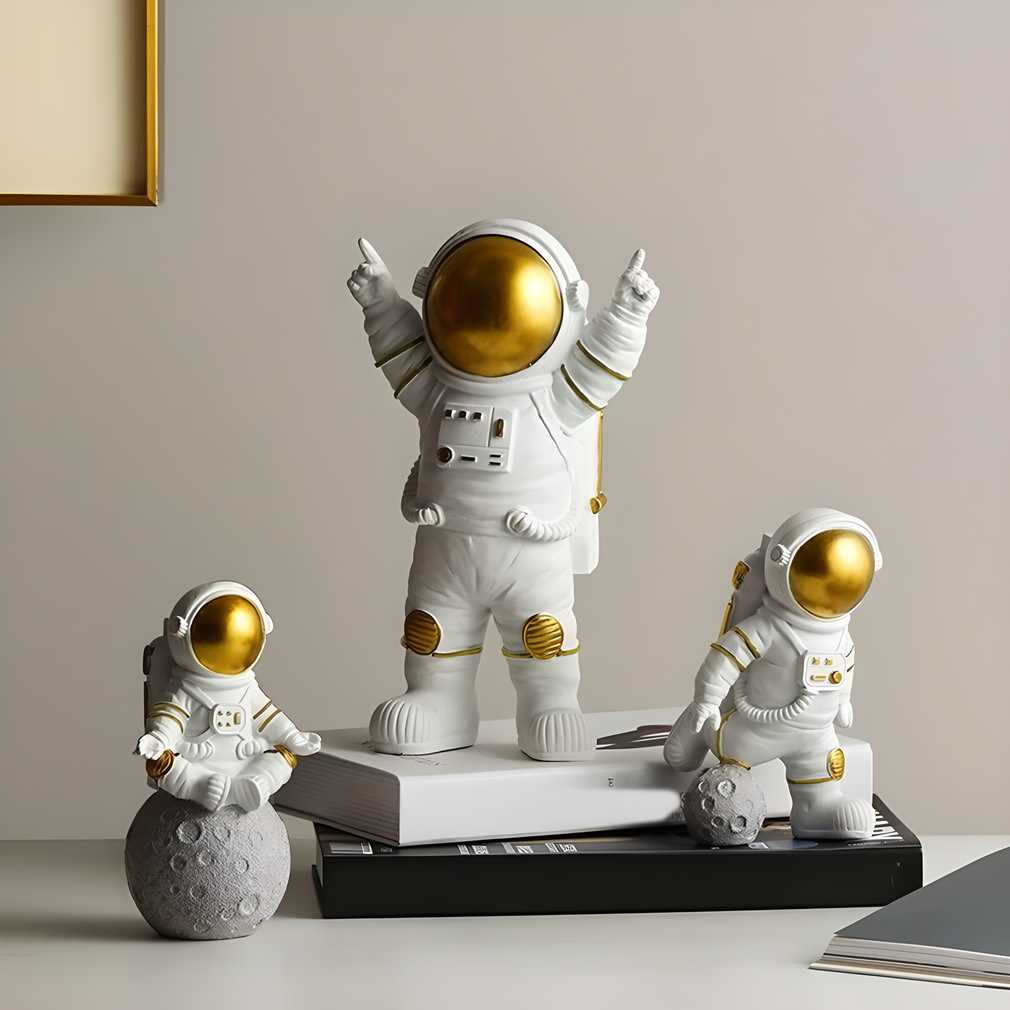 White and gold astronaut spaceman figurine trio displayed on floating shelf